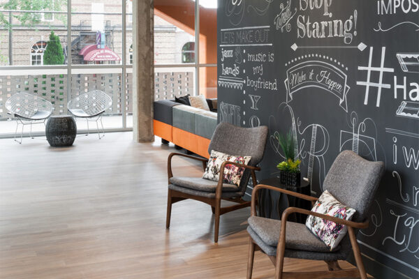 1000 Grant lounge with wood floors, modern chairs, and large chalkboard style wall.
