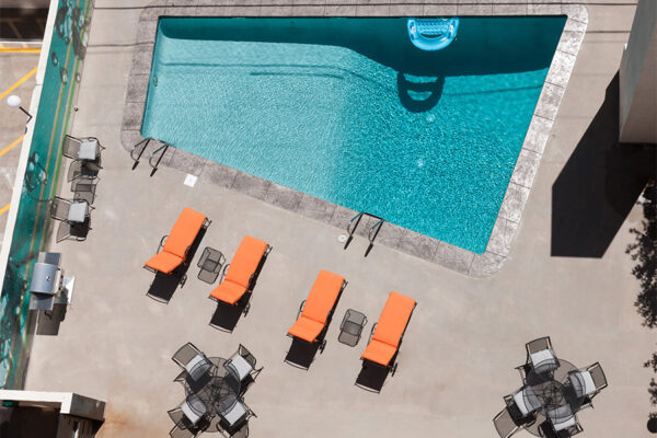 Overhead view of pool with lounge chairs and BBQ grill.