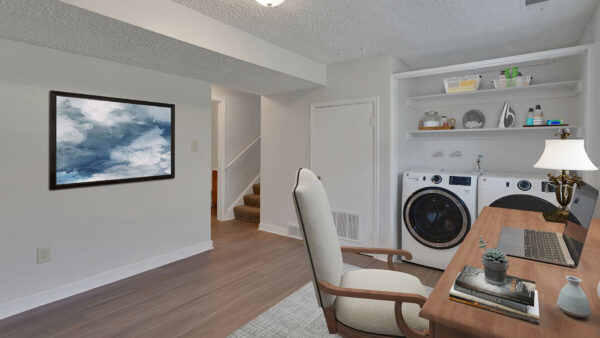Living room with office desk and in-unit washer and dryer.