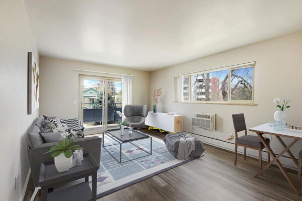 Living room with wood floor, rug, plush furniture, large window, and door to balcony.