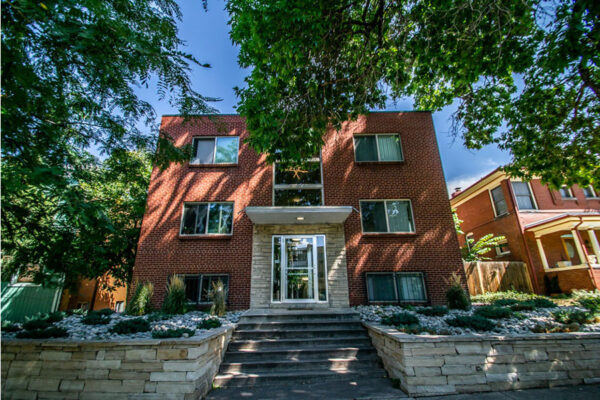 1136 York apartments with brick construction, tall trees, and glass entry foyer.