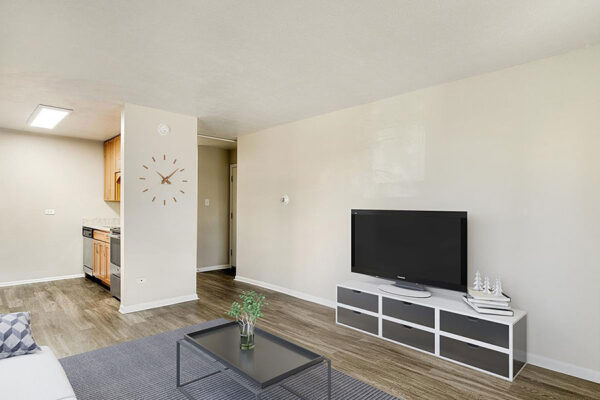 Living room with wood floor, modern furniture with console and TV, and built in clock.