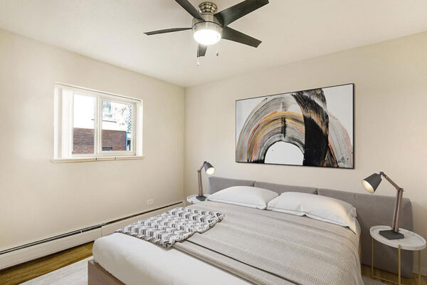 Bedroom with large plush bed, bedside tables with lamps, ceiling fan, and large window.