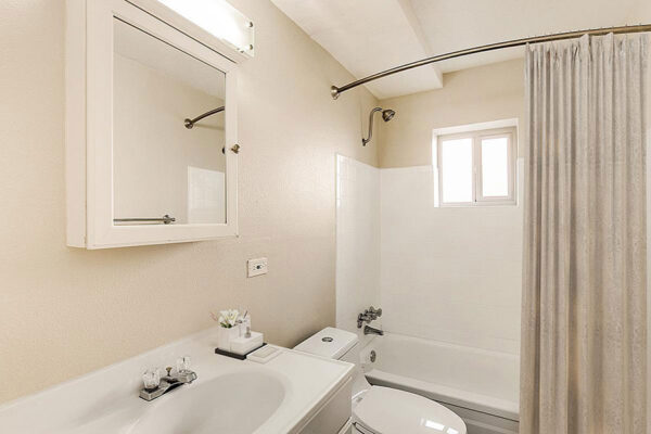 Bathroom with tan walls, tiled shower tub, smooth counter and medicine cabinet.