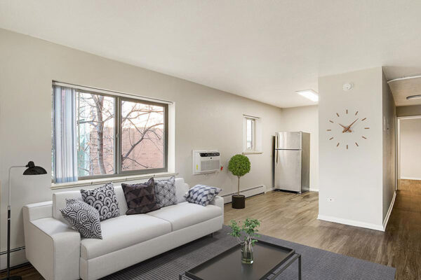 Living area with plush seating, modern furnishings, built in clock, and entry to kitchen.
