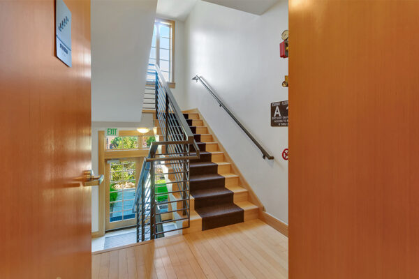 Stairway with carpet runners, metal railings, and bright windows.