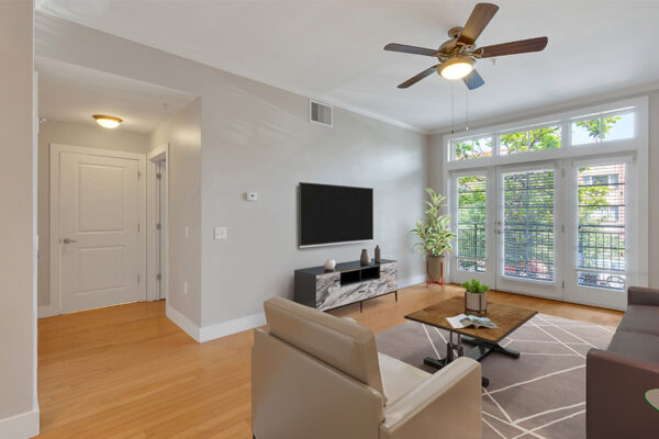 Living room with wood floor, gray walls, modern furniture, ceiling fan, and door to balcony.