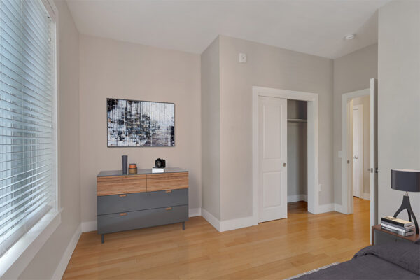 Bedroom with wood floors, warm gray walls, modern furniture, and large windows.