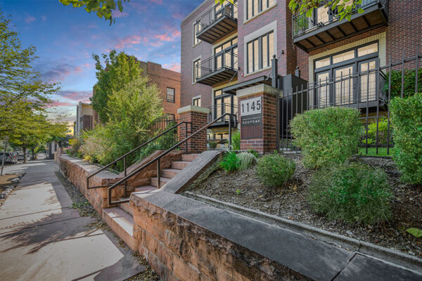 1145 Ogden apartments with contemporary style, brick construction, and iron fence.