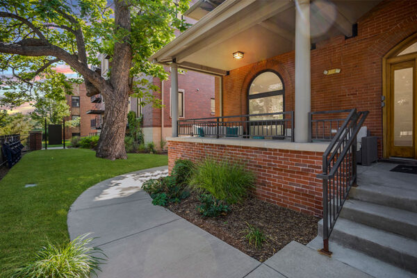 Patio with lush landscaping, outdoor furniture, and tall trees.