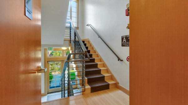 Hallway with elegant stairs and large windows providing natural light.