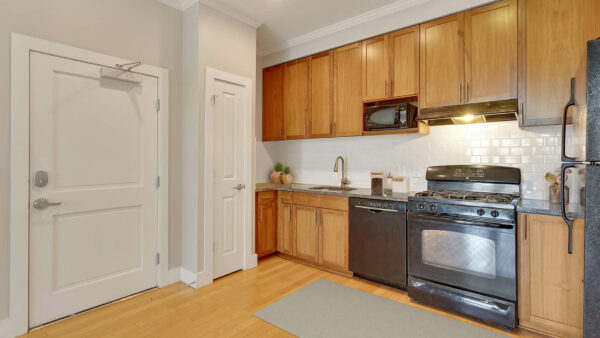 Kitchen with wood style floor and cabinets, black appliances, and large pantry.