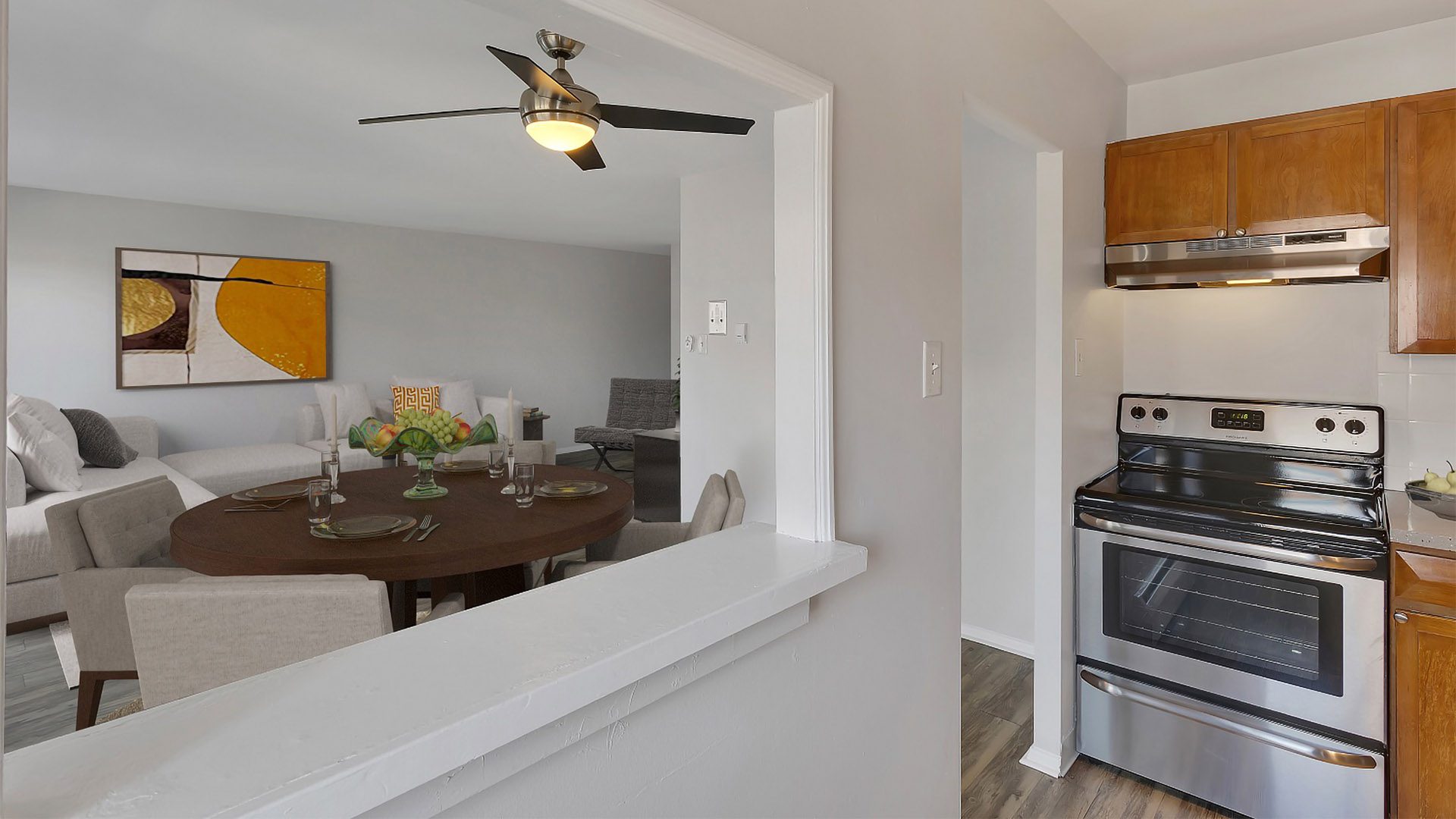 Kitchen with wood cabinets, stainless steel appliances, and window to dining and living room.