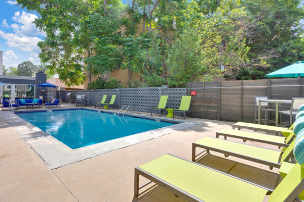 1190 Birch pool area with clean blue water, lounge chairs and tables with umbrellas.