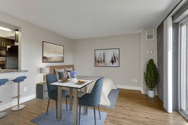 Rendering of studio living space with dining table, plush bed, breakfast bar, and framed artwork.