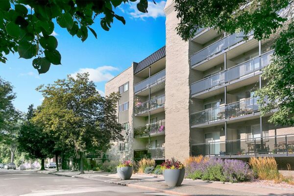 1265 Downing apartments with brick construction, tall trees, and balconies.