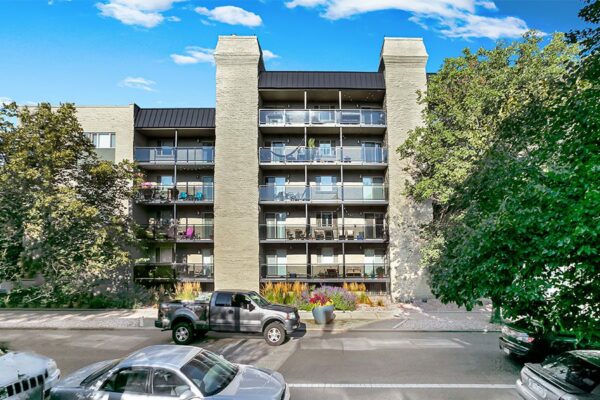 1265 Downing apartments with brick construction, tall trees, and ample parking.