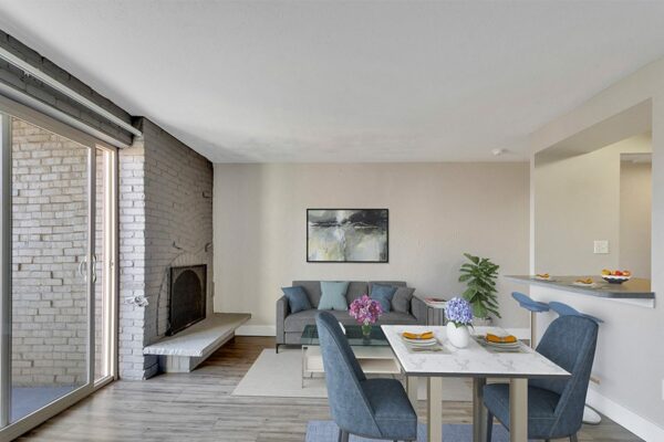 Living room with dining table, plush couch, breakfast bar, and brick accent wall with fireplace.