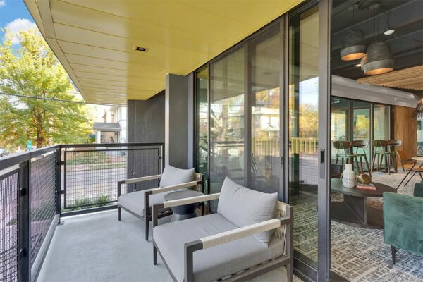 Balcony with metal railing, plush chairs, and door to lounge.