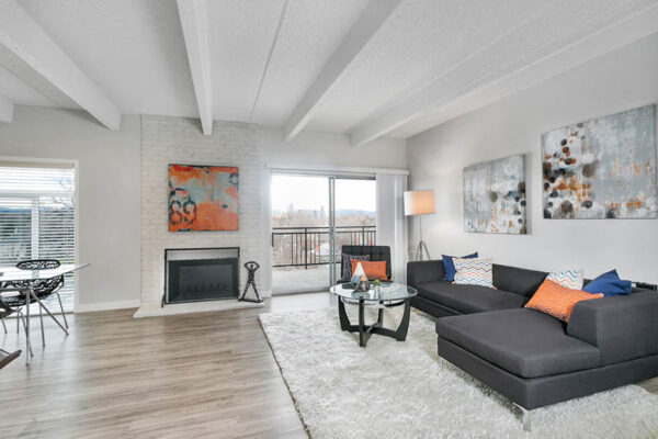 Living room with wood floor, large rug, plush sectional, and eclectic artwork and decor.