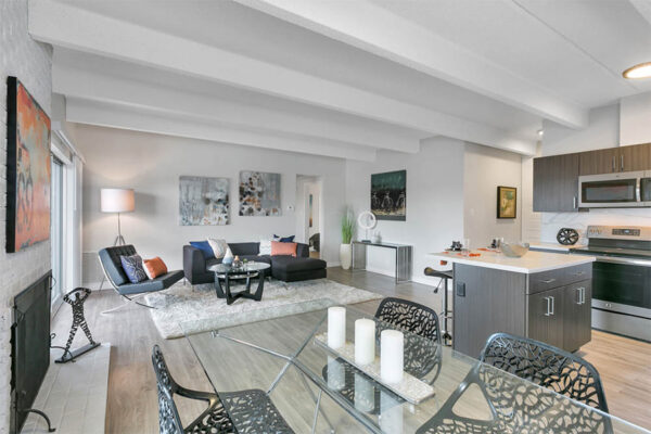 Living area with wood floors, island with stools, dining table, and sectional couch with modern decor.