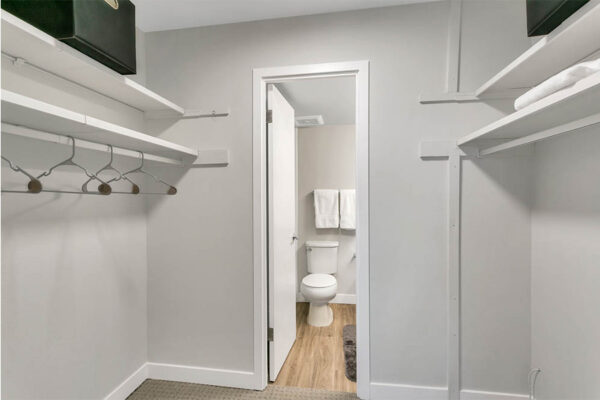 Walk in closet with built in shelves and rails with door to bathroom.
