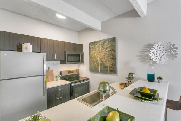 Kitchen with wood cabinets, light counters, stainless steel appliances, and breakfast bar.