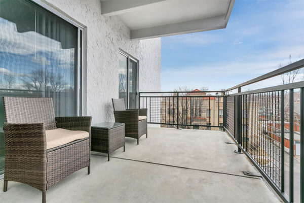 Balcony with wicker outdoor furniture and metal railings.