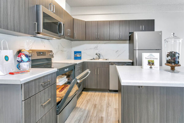 Kitchen with wood floor and cabinets, light counters, stainless steel appliances, and welcome basket.