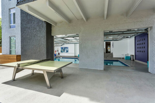 Outdoor patio with table tennis and garage doors to indoor pool.