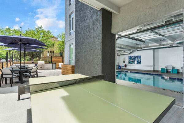 Outdoor patio with table tennis and garage doors to indoor pool.