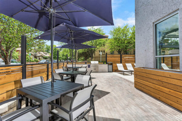 Outdoor patio with tables, umbrellas, lounge chairs, and built in BBQ grill.