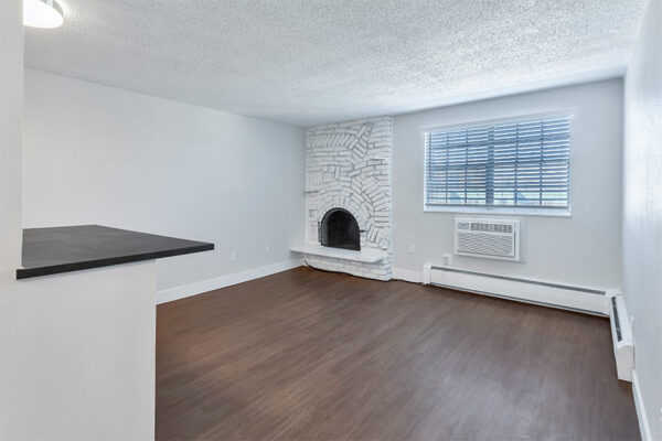 Living room with wood floor, cool grey walls, baseboard heater, and brick accent wall with fireplace.