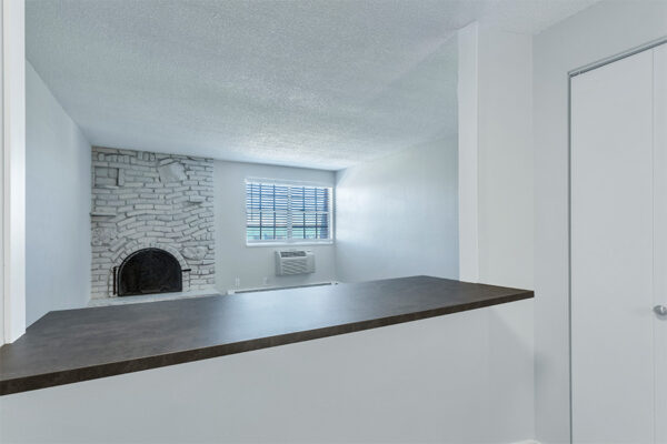 Breakfast bar with opening between kitchen and living room with fireplace.
