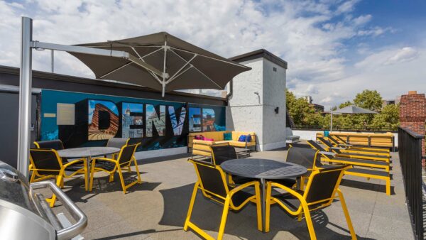 Rooftop patio with lounge chairs and painted Denver mural.