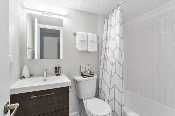Bathroom with wood cabinets, white counter, medicine cabinet, and tiled shower tub.