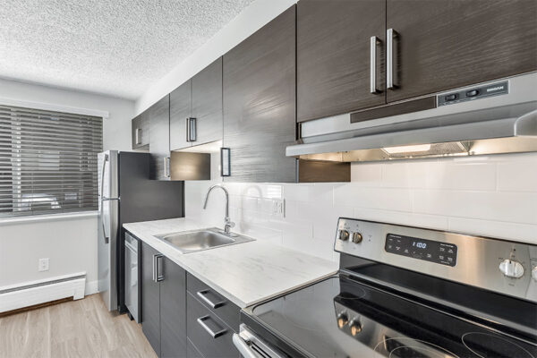 Kitchen with wood cabinets, light counters, stainless steel appliances, and tiled backsplash.