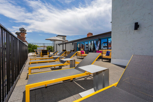 Rooftop patio with lounge chairs and Denver mural.