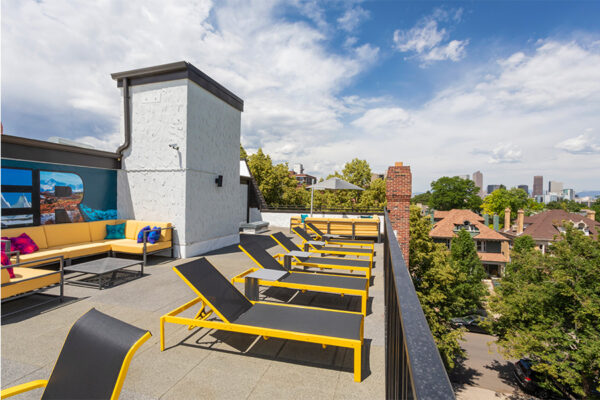 Rooftop patio with lounge chairs and outdoor sectional overlooking Denver.