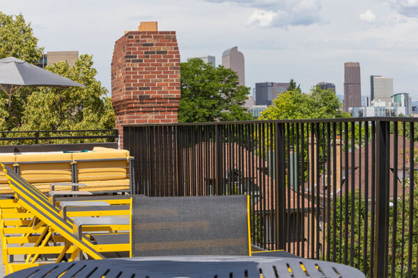 Rooftop patio with lounge chairs and metal railing overlooking Denver.