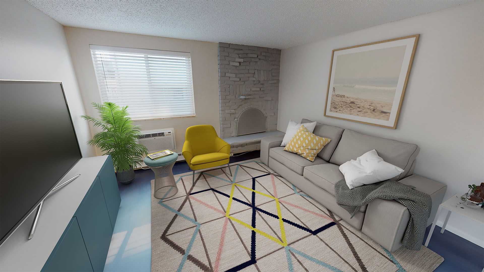 Living room with geometric rug, plush couch and chair, TV on media stand, and brick fireplace.