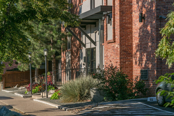 Exterior of 1430 Humboldt with brick construction, lush landscaping, and tall trees.