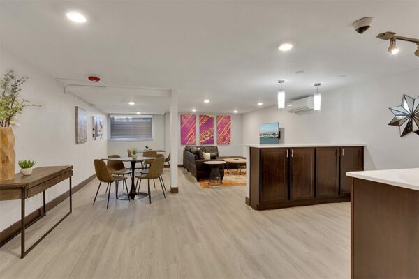 Demo kitchen with wood floor and cabinets, white counters, eclectic decor, and pendant lights.