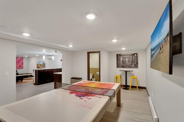 1430 Humboldt game room with table tennis, large TV, and bar tables with stools.