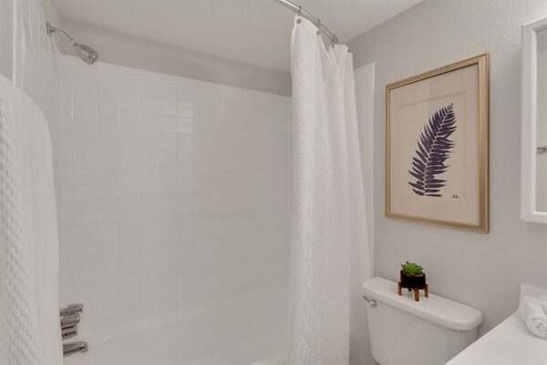 Bathroom with framed artwork and tiled shower tub.