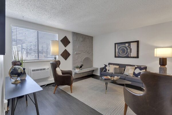 Living room with wood floor, rug, modern furniture, and brick fireplace.