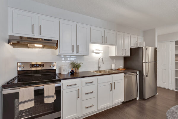 1430 Humboldt kitchen with wood floor, white cabinets, dark counters, and stainless steel appliances.