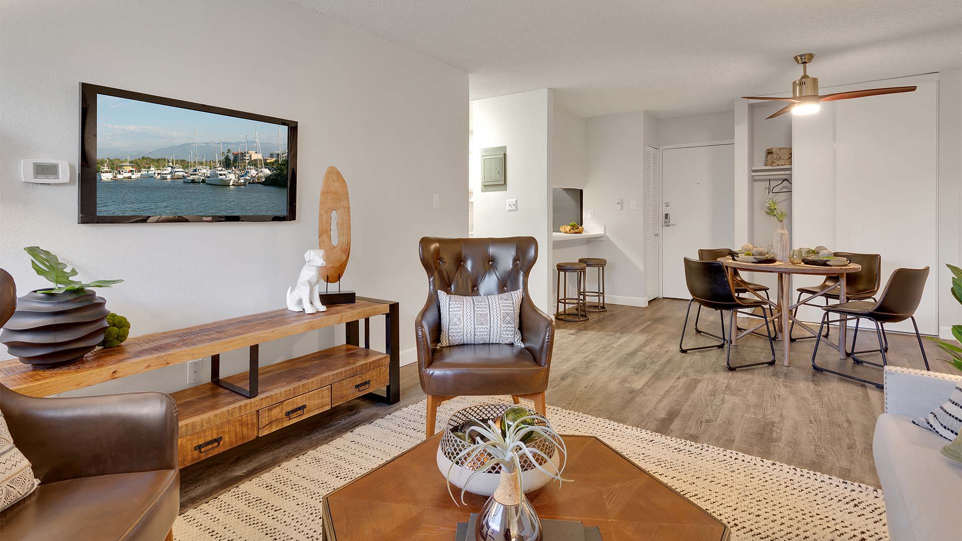 Living area with rich furniture, dining table with chairs, large closet, and breakfast bar with stools.