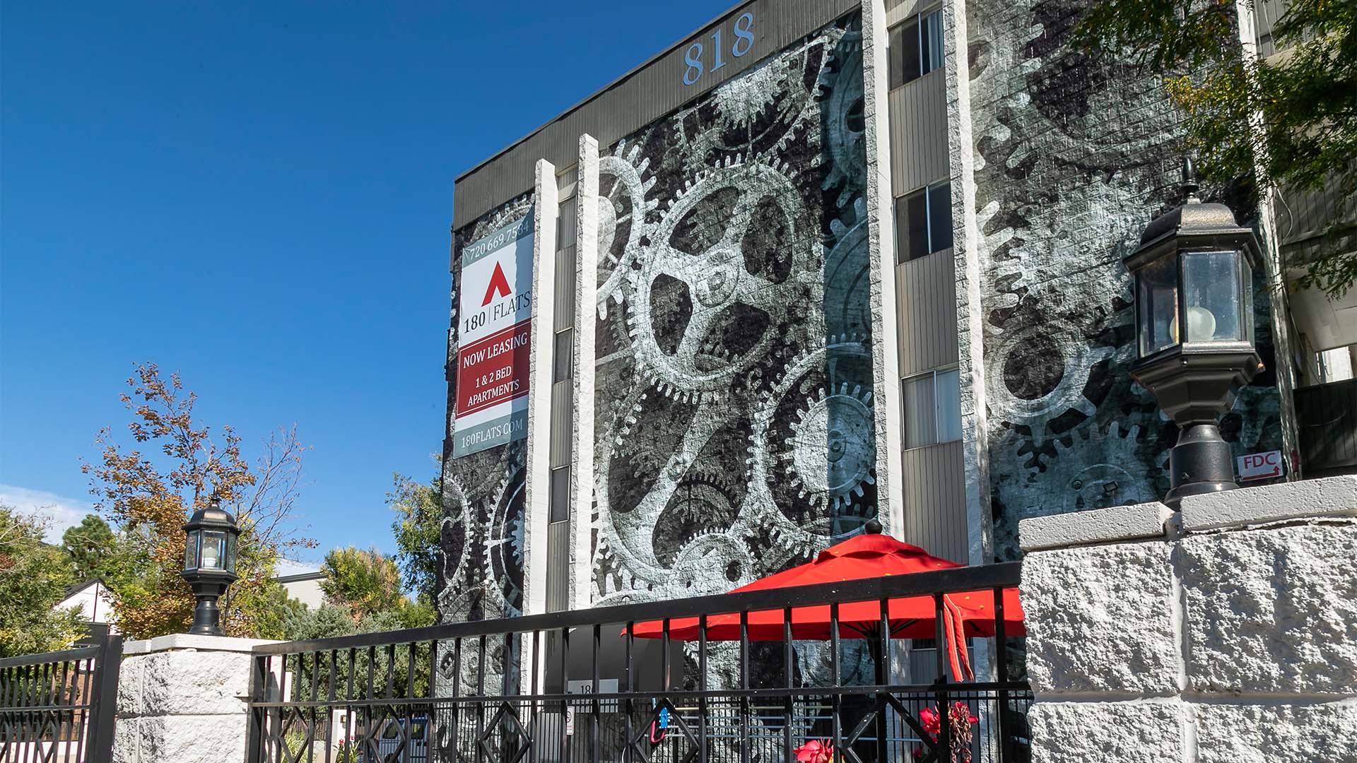 180 Flats apartments with large clockwork graphic and fenced patio area.