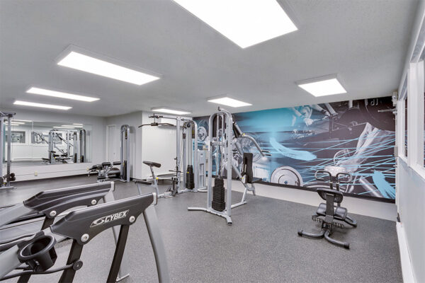 Fitness center with weightlifting wall graphic, water fountain, and weight machines.
